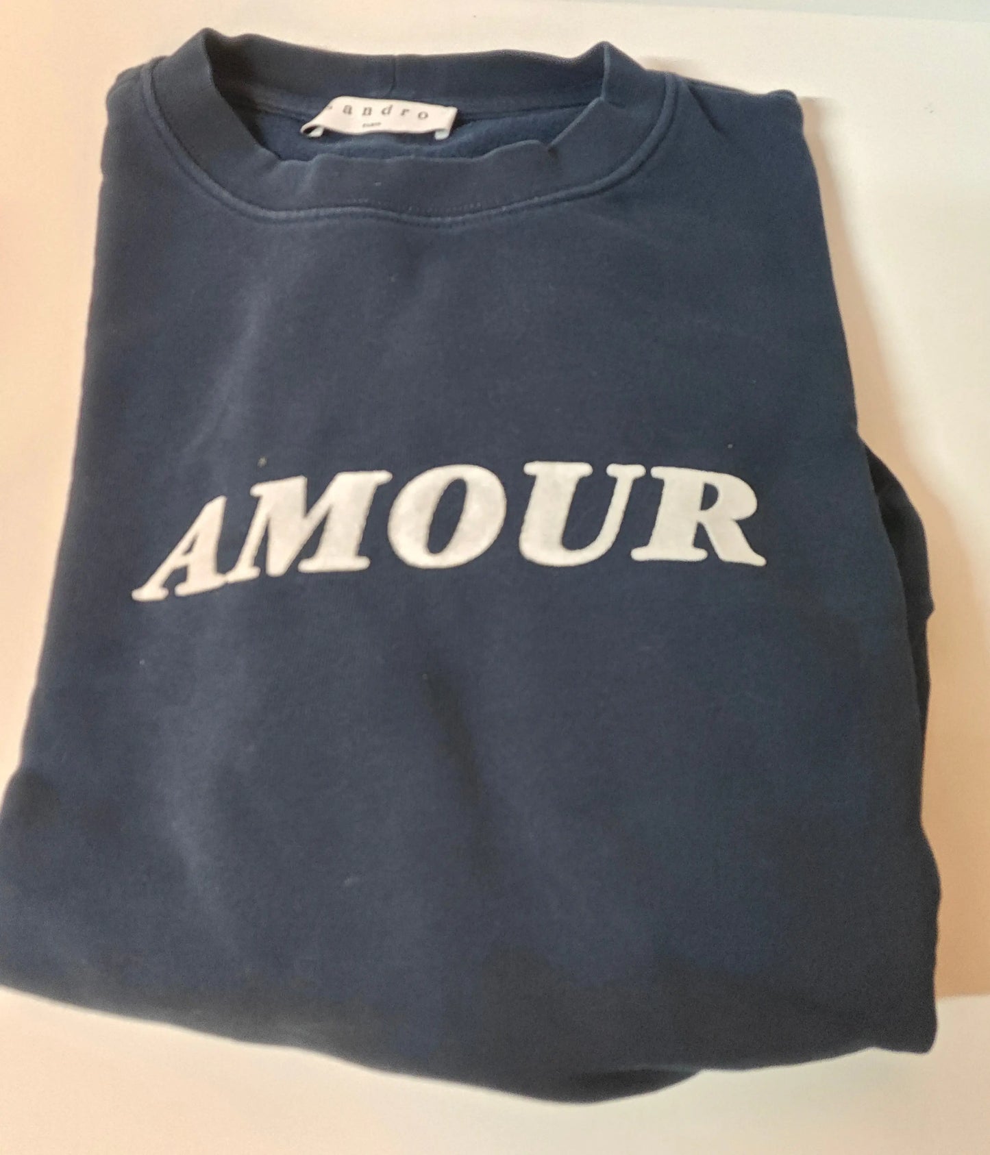 Sweat bleu marine avec inscription "AMOUR" en blanc de Sandro, plié.
