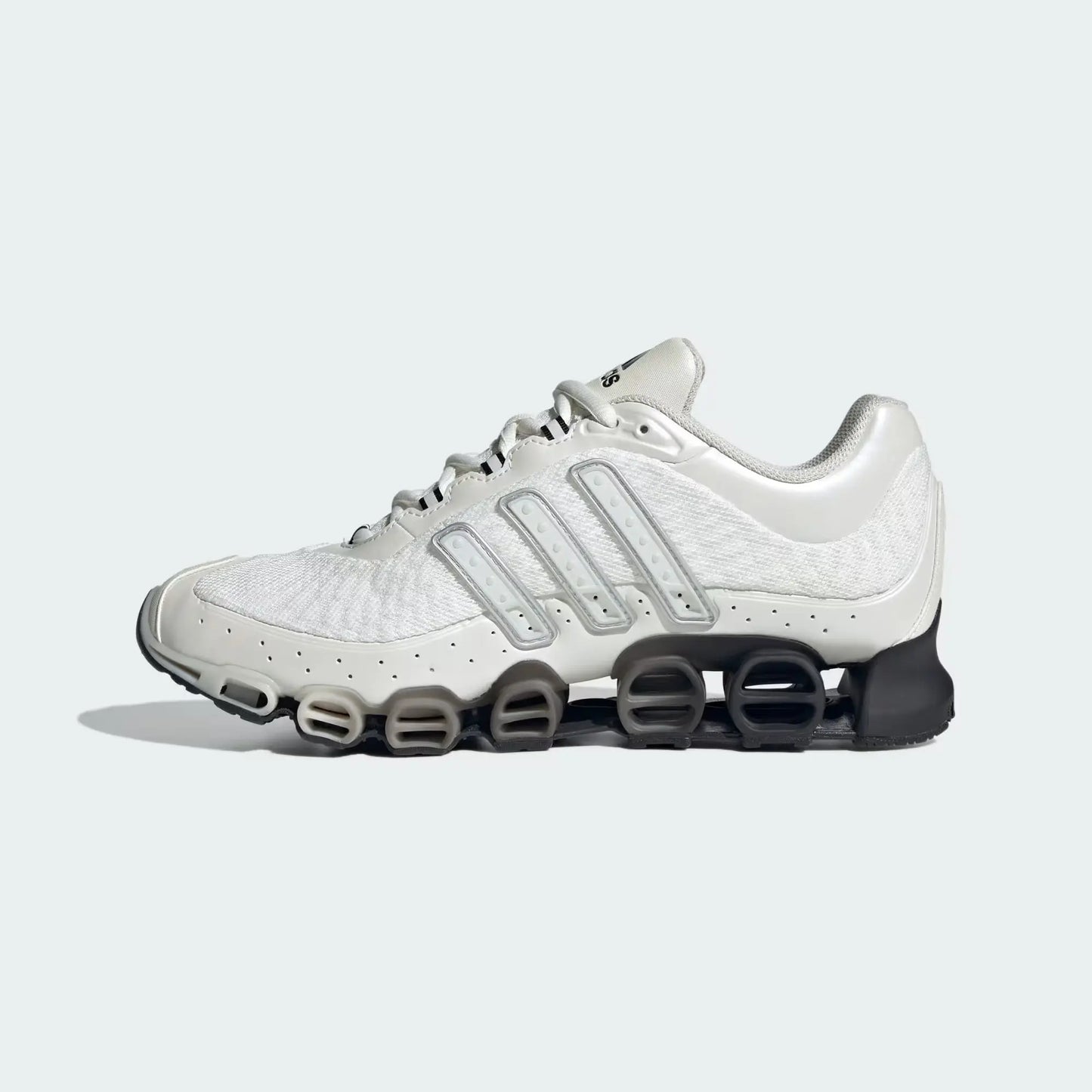 Chaussure de sport blanche par Adidas, avec détails gris argentés et semelle à ressorts noirs.