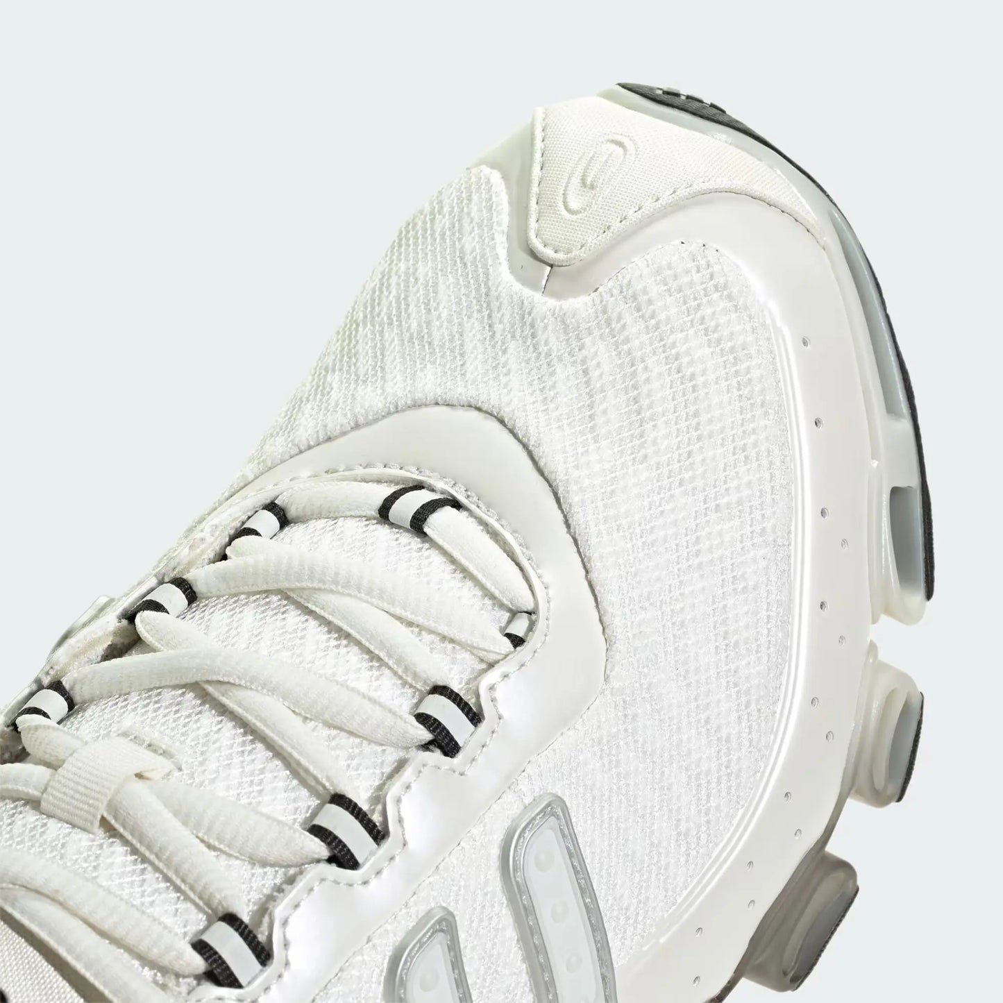 Chaussure de sport blanche par Adidas, avec des lacets blancs et des détails rayés noirs.