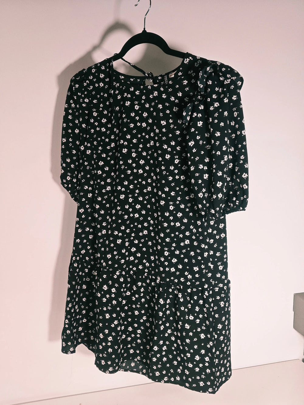 Robe fleurie noire de H&M, avec motif floral blanc, manches trois-quarts bouffantes et coupe trapèze à volants.