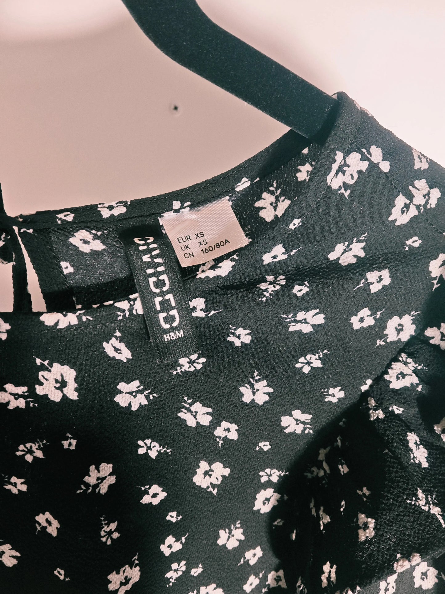 Robe noire à fleurs blanches de H&M, avec étiquette de taille visible.