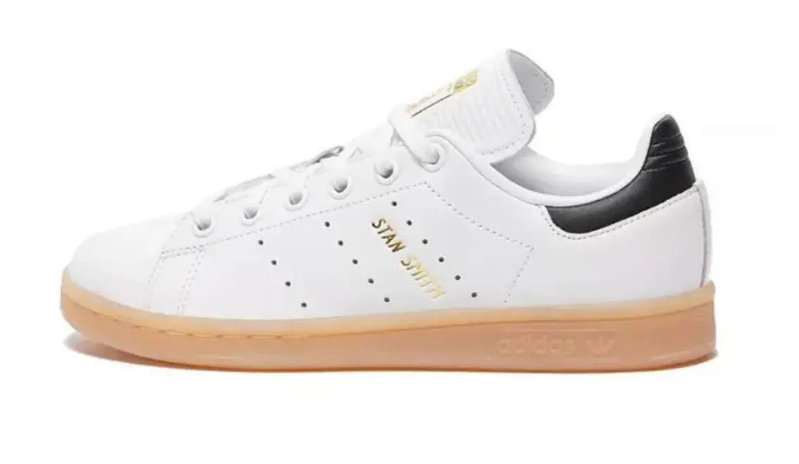 Baskets Stan Smith en cuir blanc par Adidas, avec semelle en gomme et détail noir au talon.