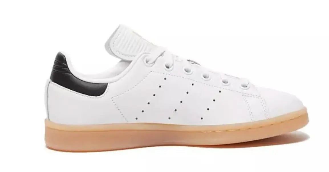 Sneaker Stan Smith en cuir blanc par Adidas, avec détails noirs au talon et semelle en gomme.