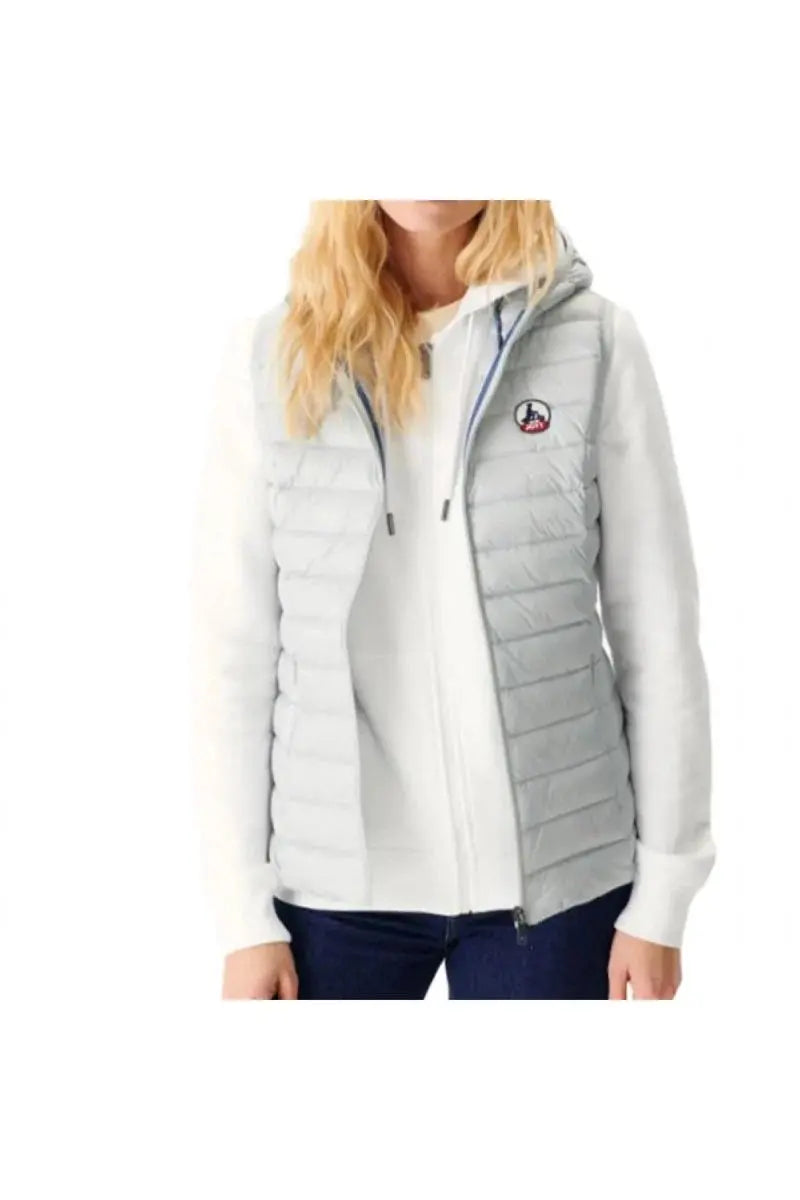 Doudoune sans manches grise de Jott avec capuche, portée sur un pull blanc et un jean bleu.