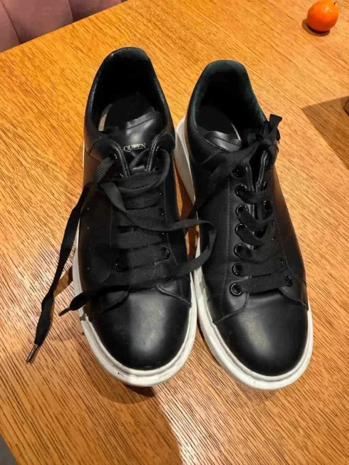 Baskets noires en cuir par Alexander McQueen, avec des lacets noirs et semelles blanches épaisses.