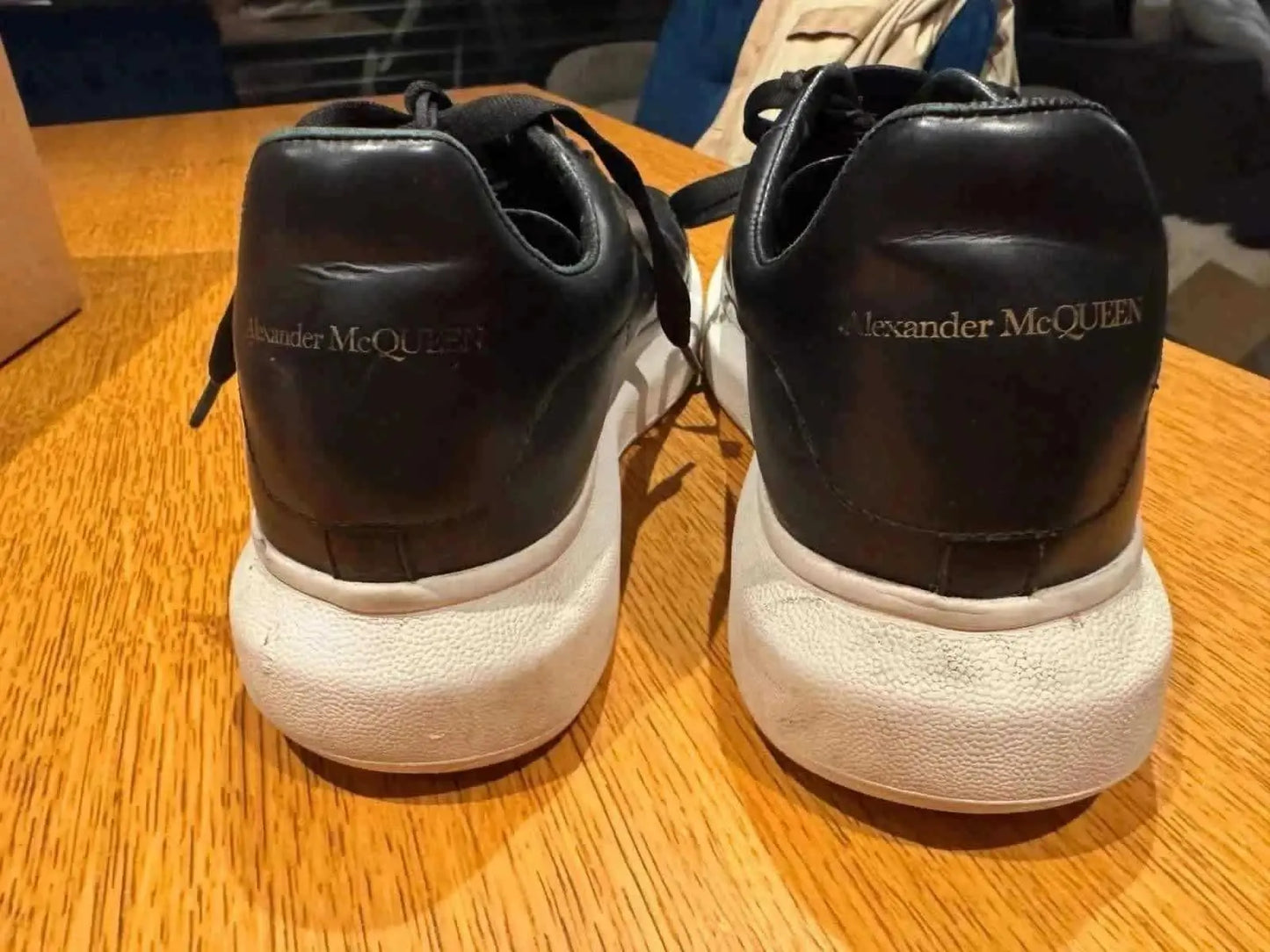 Baskets noires de seconde main par Alexander McQueen, vue arrière sur table en bois clair.