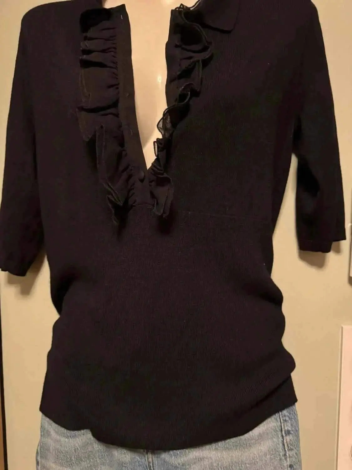 Blouse noire à manches courtes de Kookai, avec détails volants sur le devant et tricot côtelé.