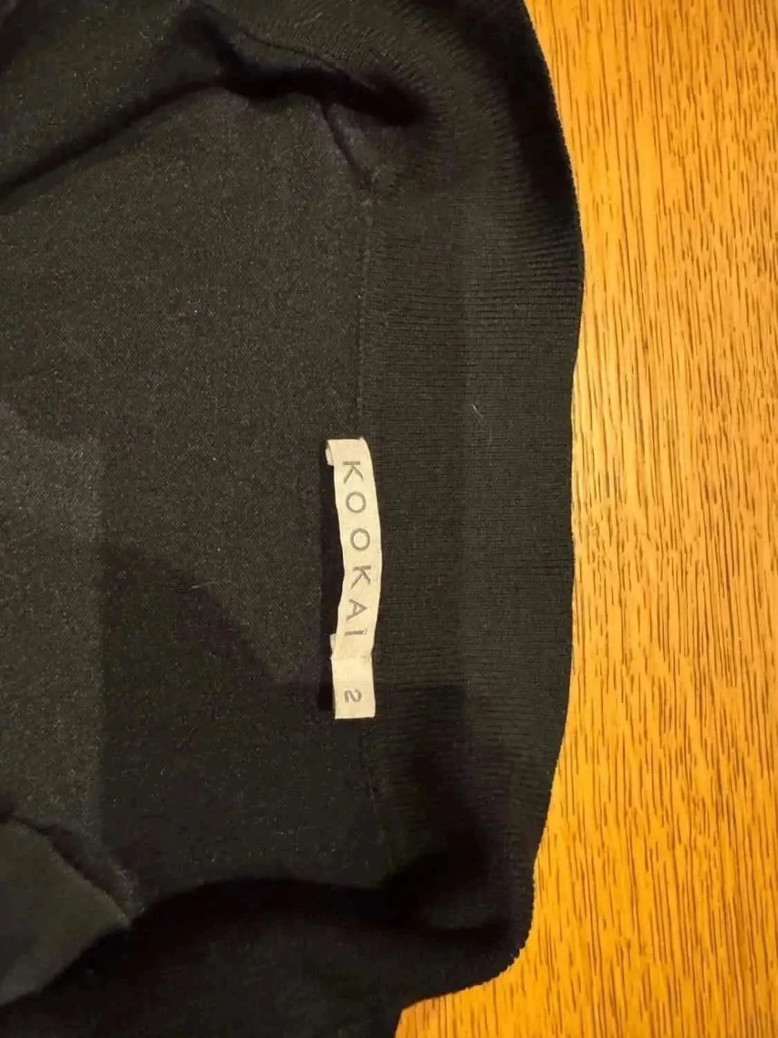 Blouse noire by Kookai, avec des détails volants et une texture élégante.