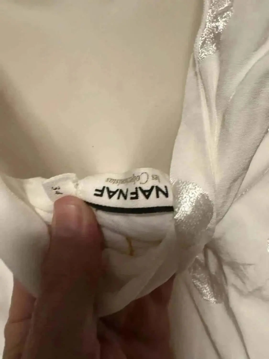Robe blanche à pois argentés de NAF NAF, en taille 36, tenue à la main.