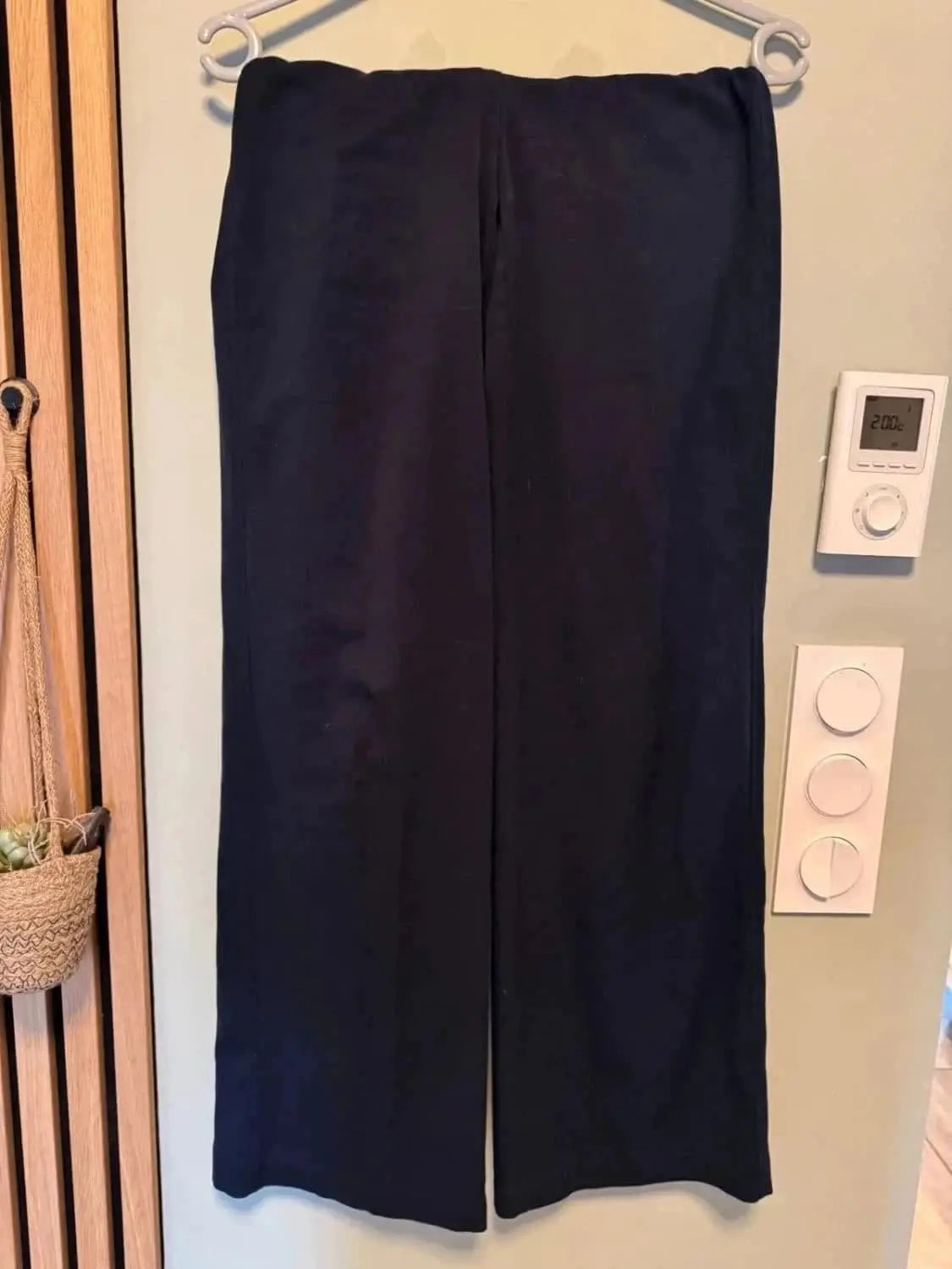 Pantalon bleu marine de Bershka, suspendu sur un cintre, avec une coupe droite et fluide.