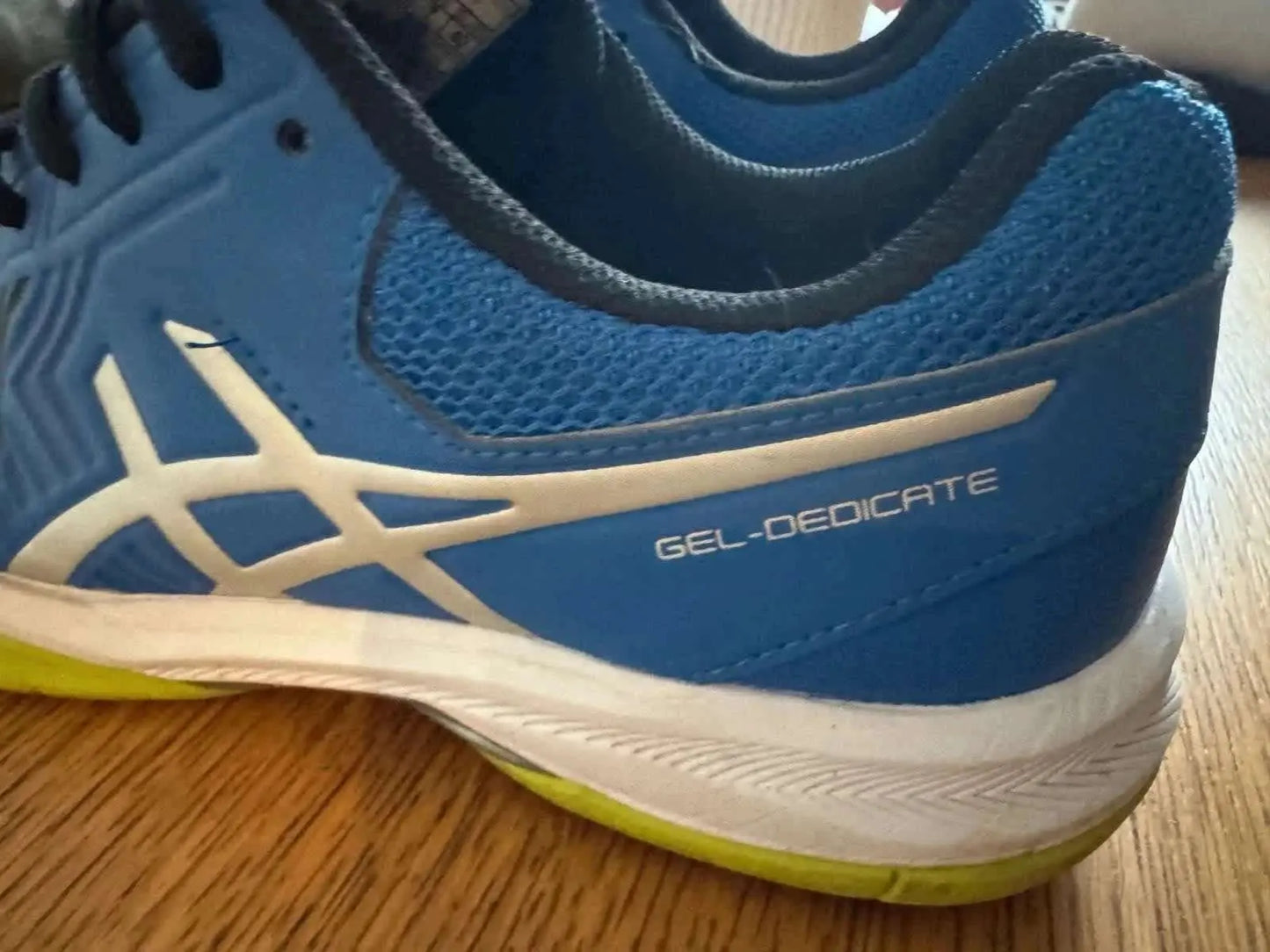 Chaussure de sport bleues par ASICS, avec logo blanc et inscription « GEL-DEDICATE » argentée sur le côté.