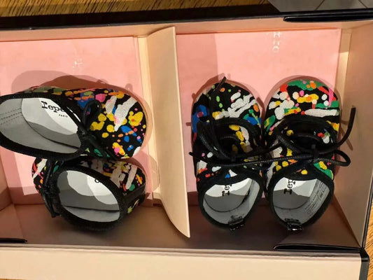 Chaussons Repetto pour bébé noirs et multicolores de Repetto, à motifs de confettis colorés, présentés dans leur boîte.