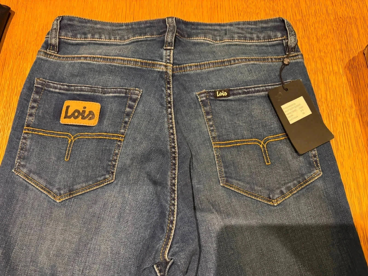 Jean bleu en denim de Lois, avec poches arrière et étiquette de la marque.