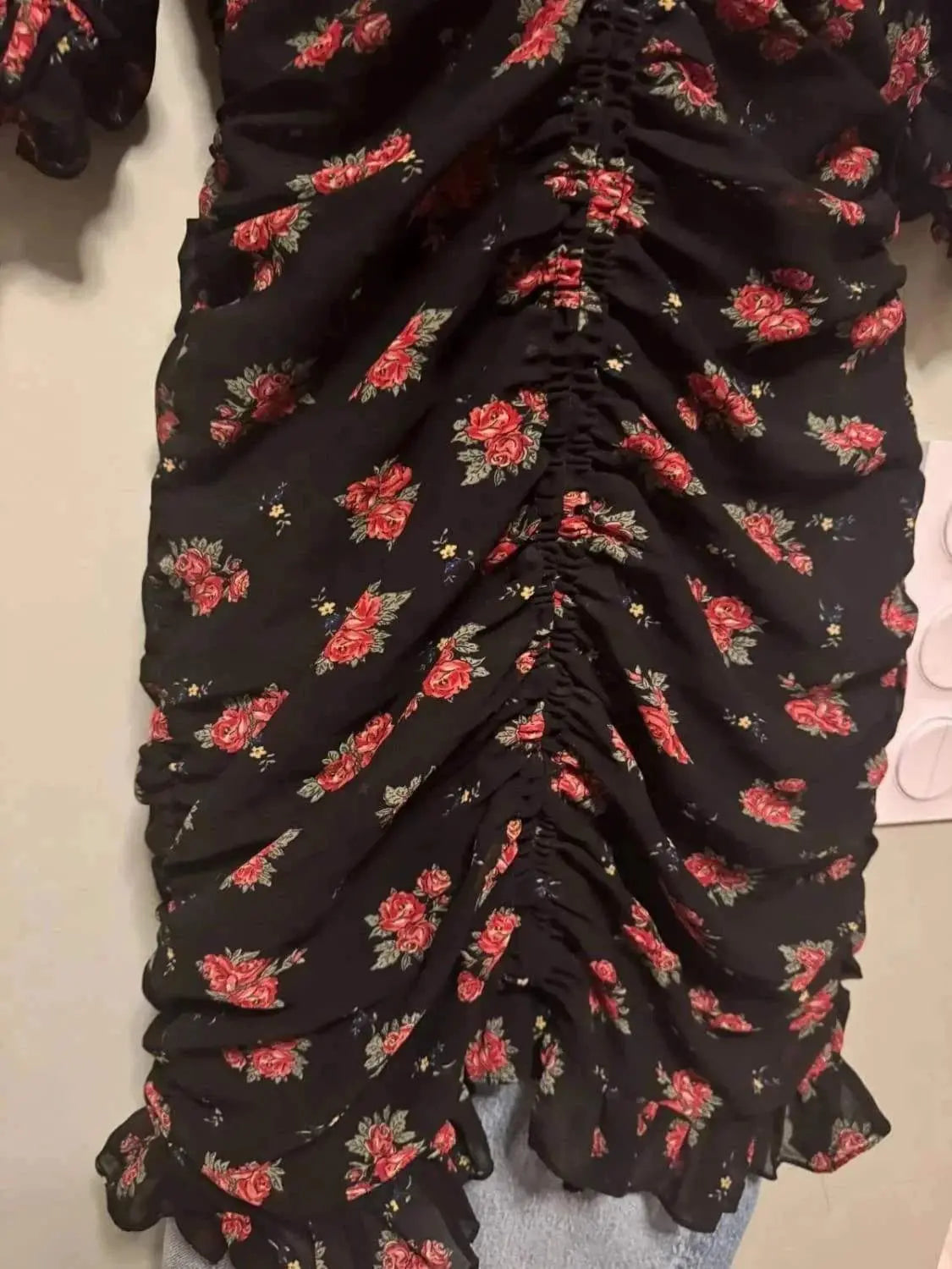 Robe noire à fleurs de Zara, avec un motif floral rouge et vert, et un effet froncé sur le devant.
