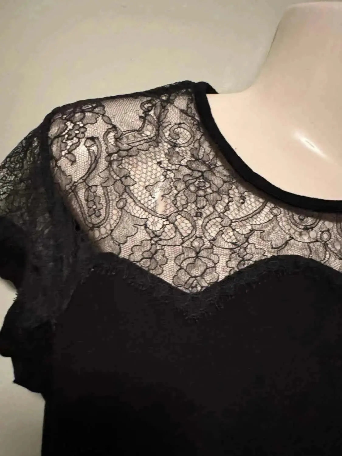 Haut noir avec empiècement en dentelle de Maje, orné de motifs floraux et de bordures festonnées.