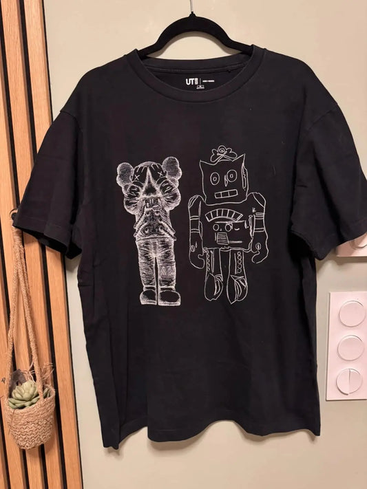 T-shirt noir Uniqlo x KAWS x Andy Warhol avec des imprimés graphiques blancs de personnages de dessins animés.