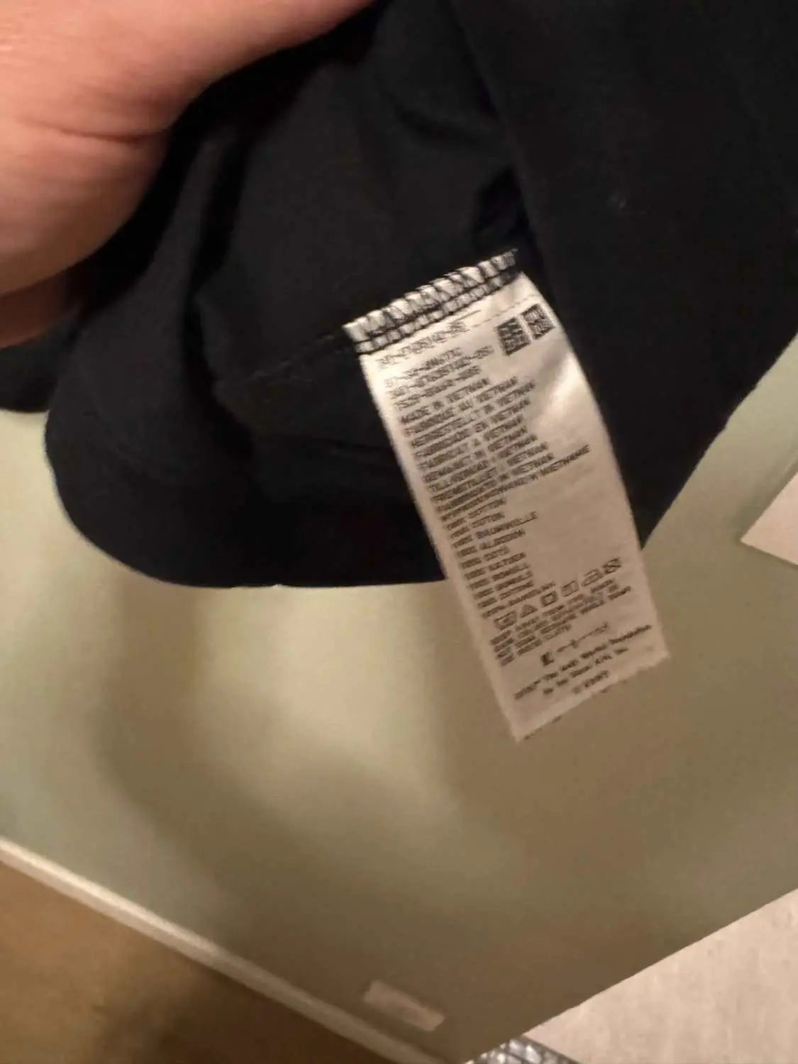 T-shirt noir de seconde main Uniqlo x KAWS x Andy Warhol, avec étiquette d'entretien visible.