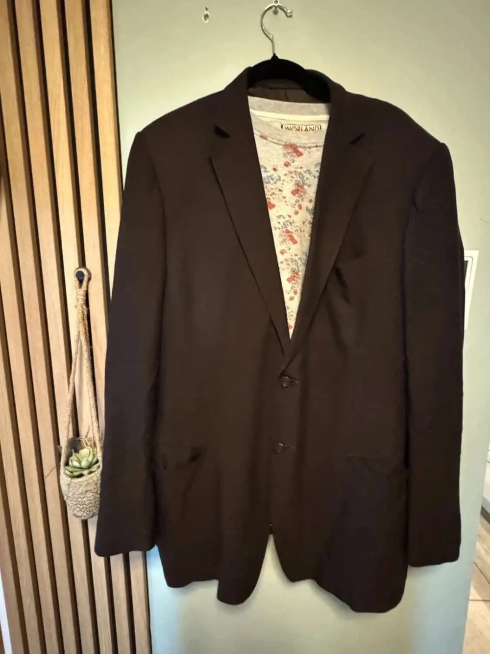 Blazer marron foncé de Zegna avec une doublure à motifs floraux, suspendu à un cintre.