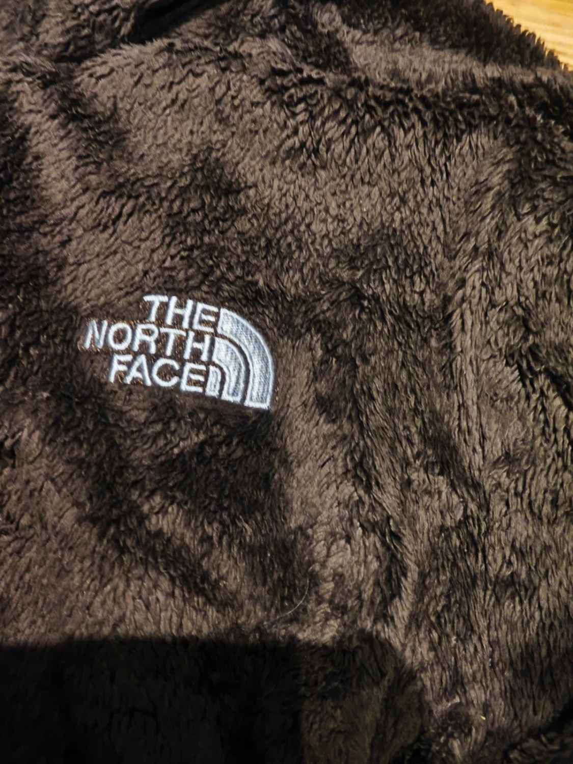 Veste polaire marron en pilou de The North Face, avec le logo brodé sur la poitrine.