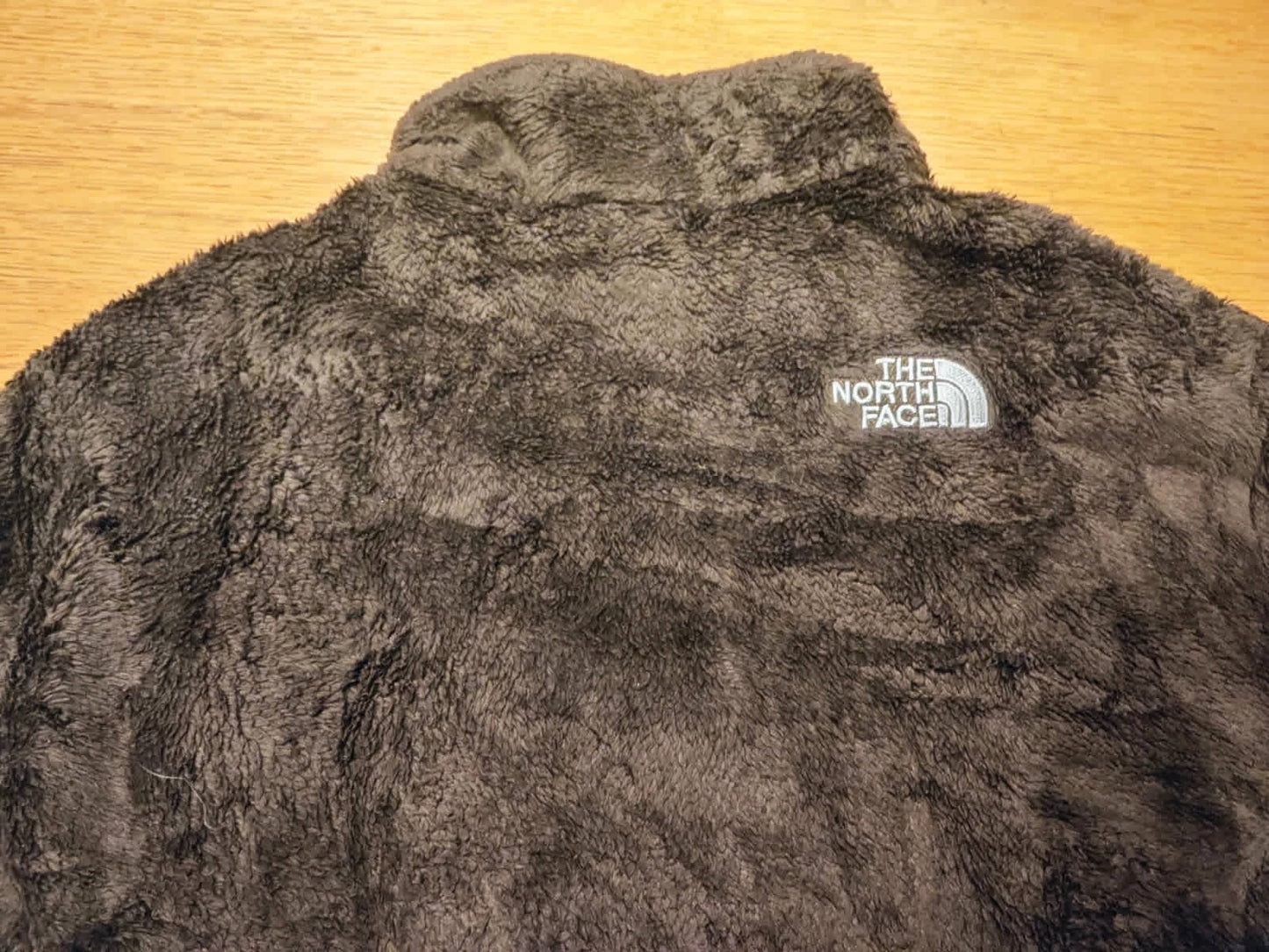 Veste polaire marron duveteuse de The North Face, avec logo brodé sur la poitrine.