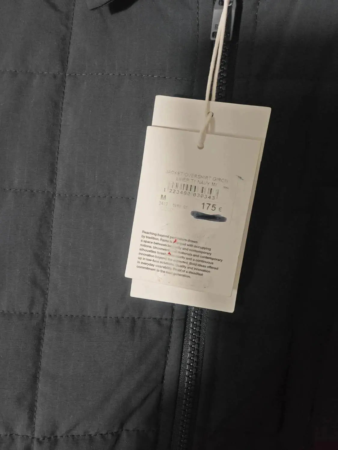 Veste matelassée marine de chez Rains, avec étiquette de prix.