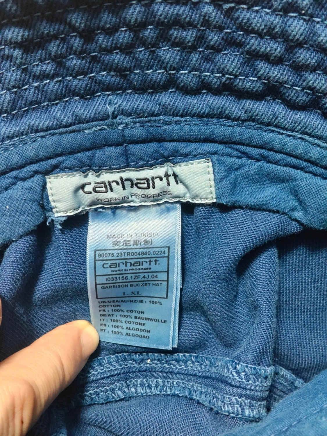 Bob bleu en coton, de Carhartt, avec une étiquette de marque visible et des coutures décoratives.