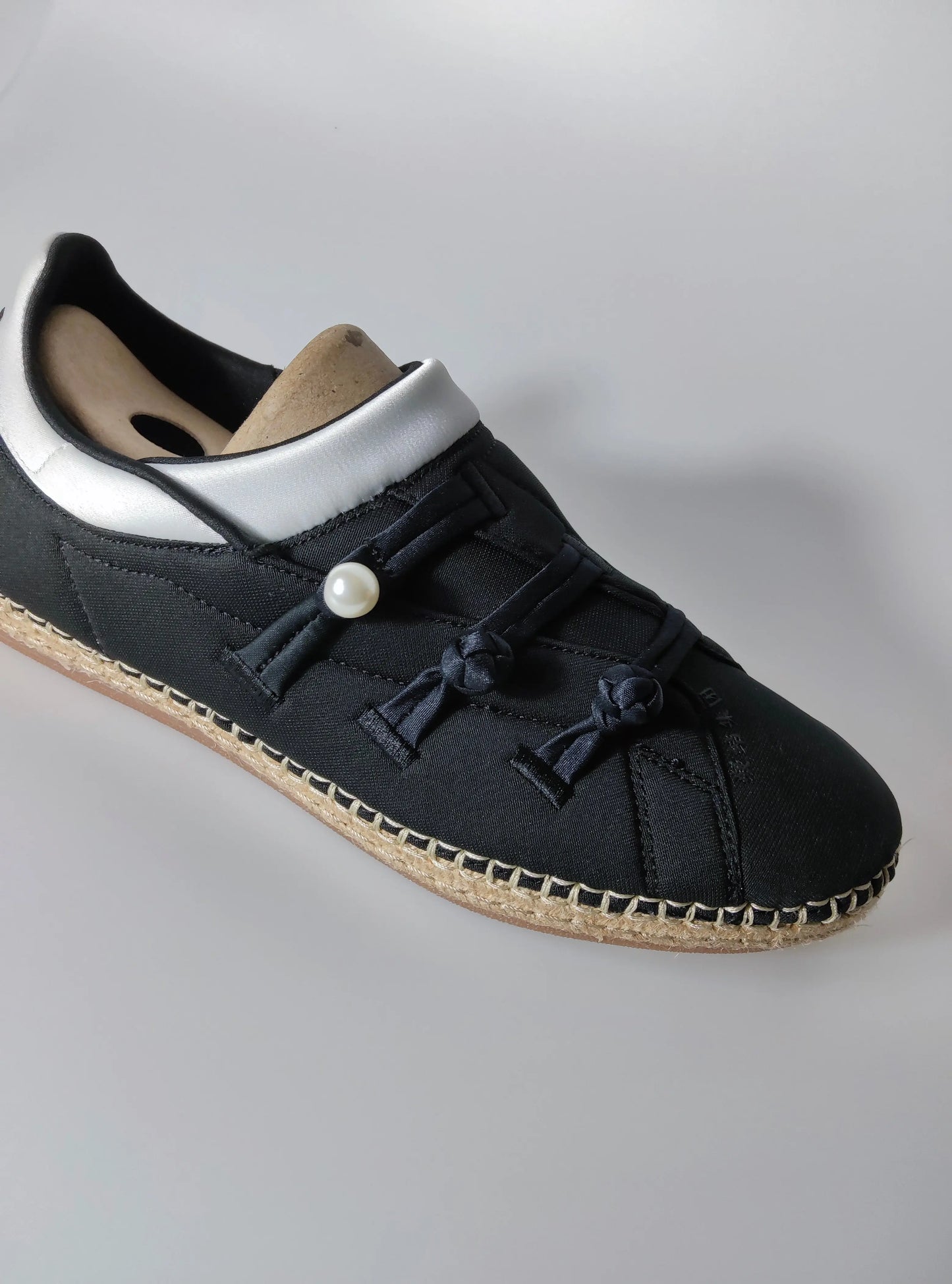 Espadrille noire en tissu, d'Adidas, avec des lacets décoratifs noués et une perle ornementale.