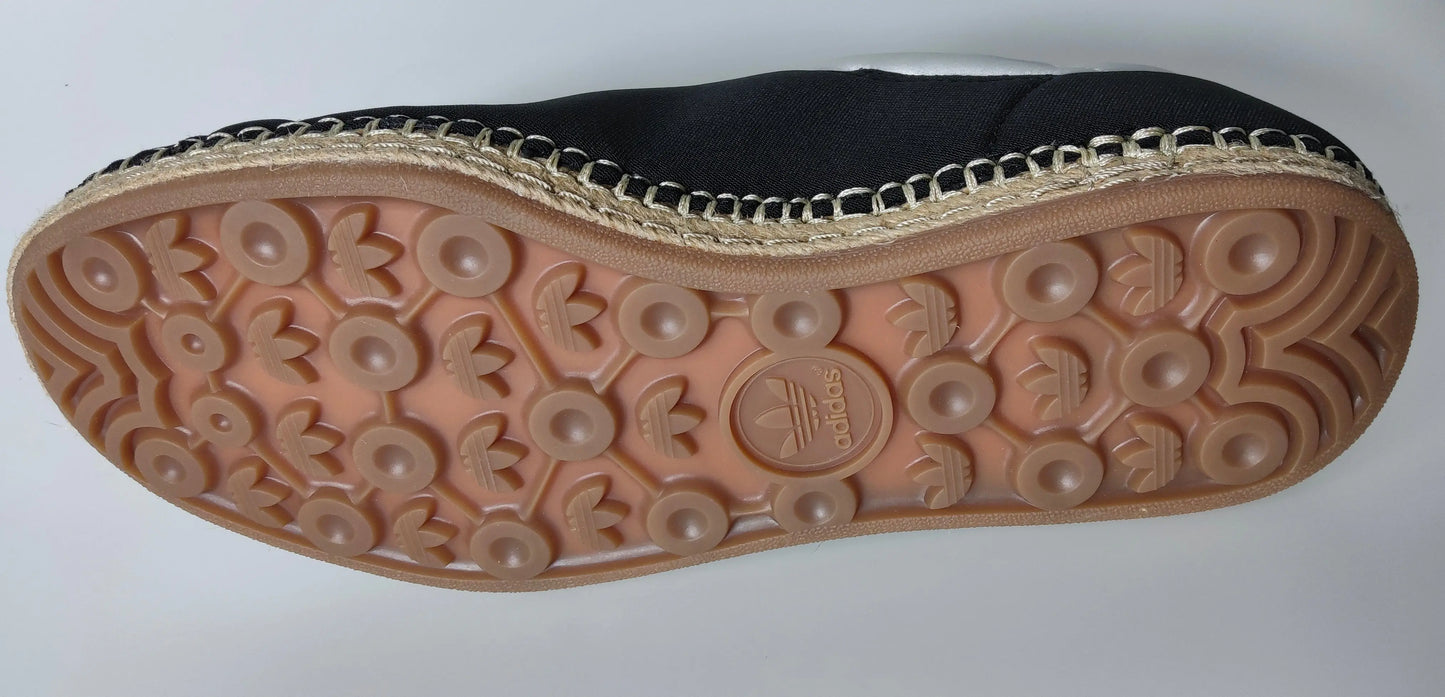 Espadrille noire de marque Adidas, avec semelle marron à motif trèfle.
