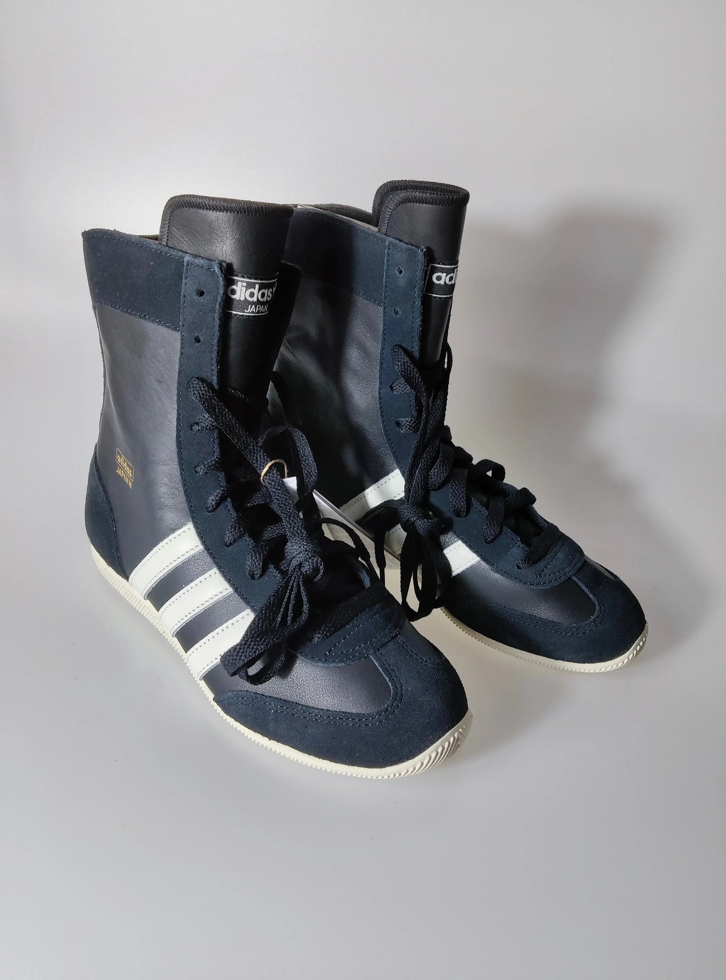 Baskets montantes noires et blanches, de Adidas, avec lacets et trois bandes blanches.
