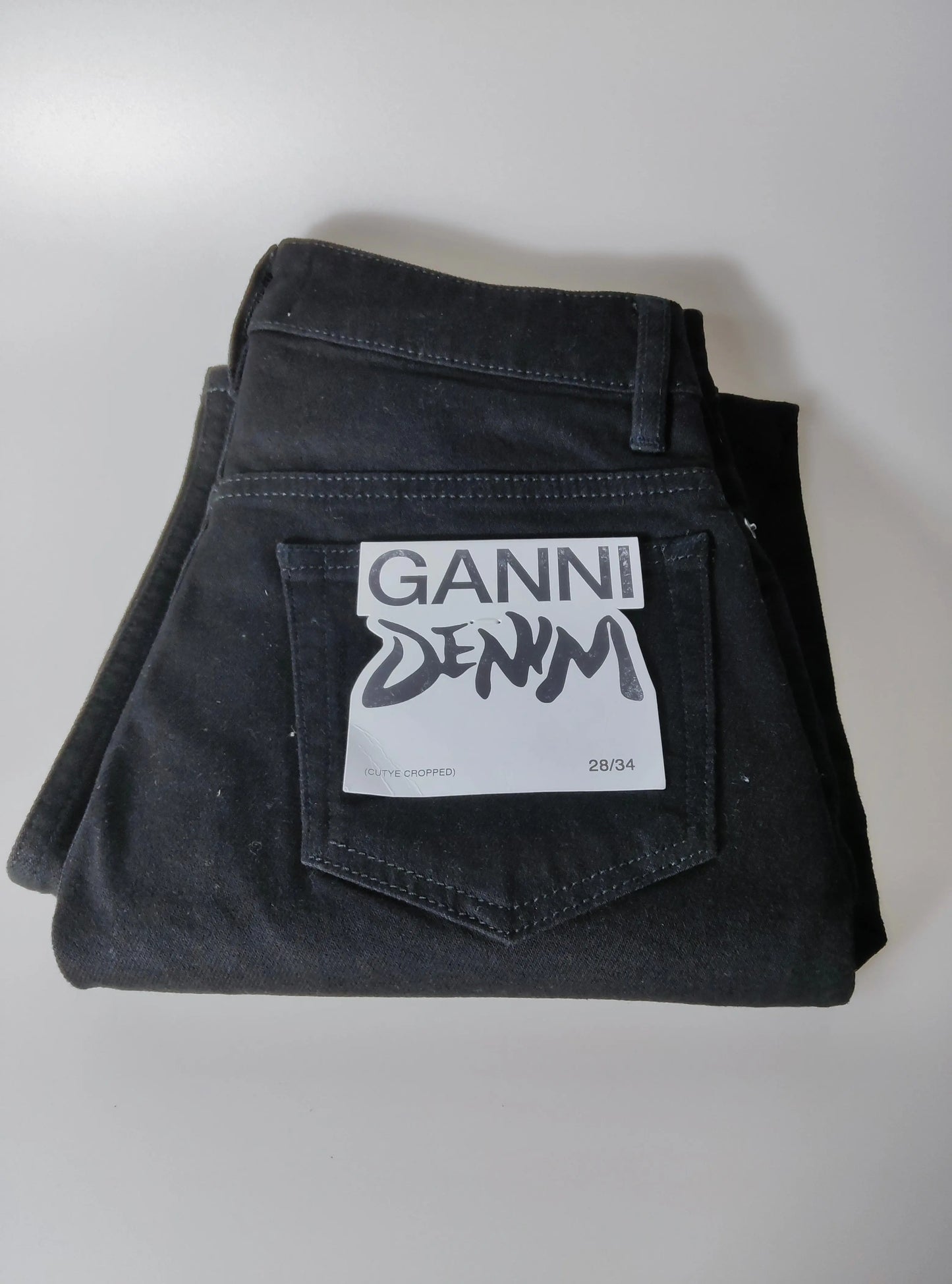 Jean noir en coton organique par Ganni, avec étiquette de la marque sur la poche arrière.