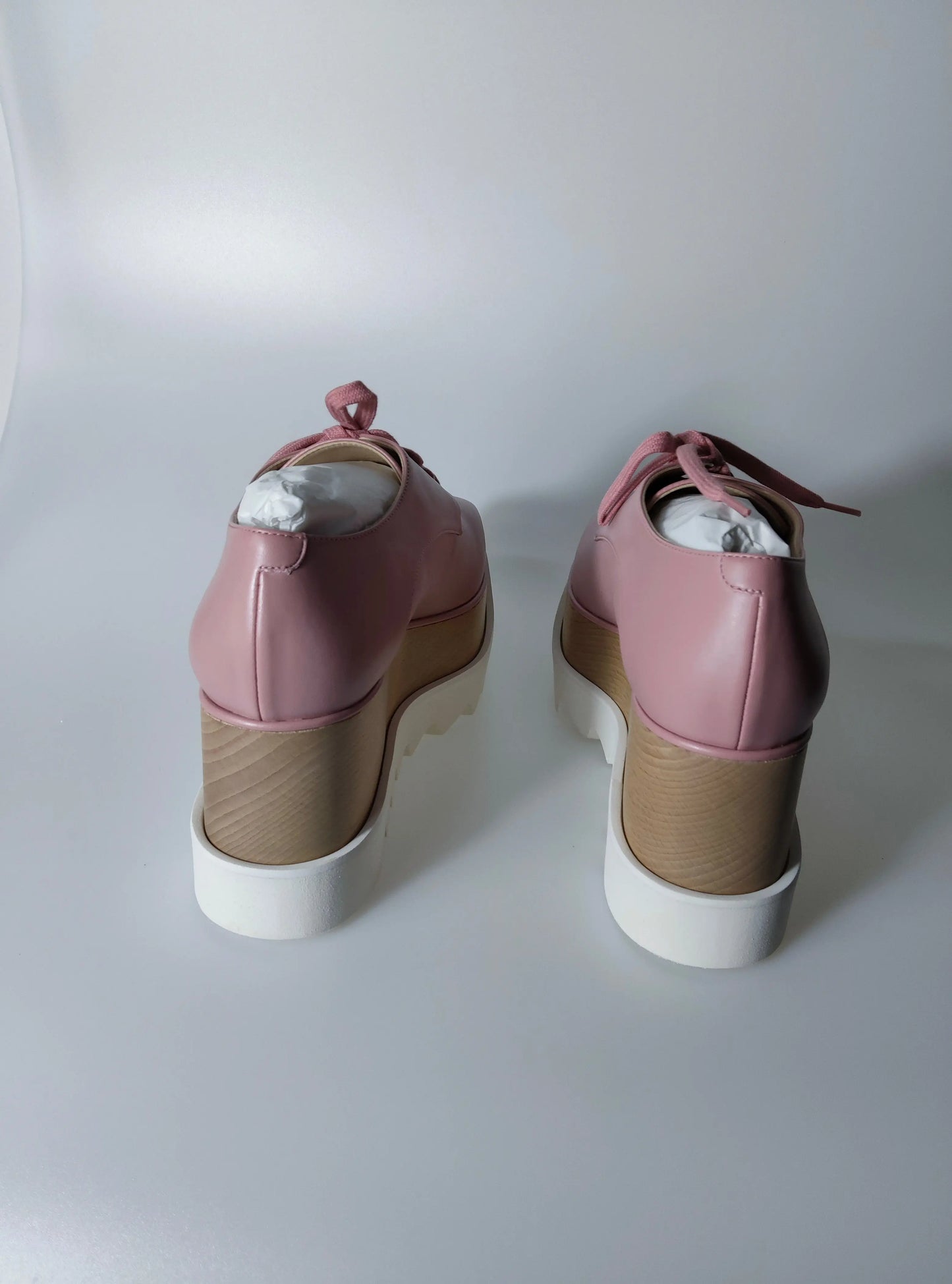 Chaussures compensées roses pour femmes par Stella McCartney avec lacets roses et semelles blanches.
