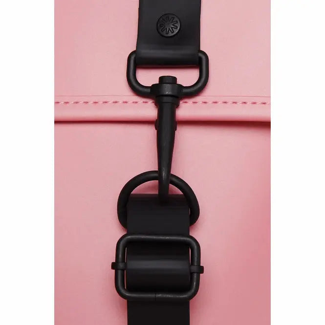 Sac à dos rose Backpack Mini de Rains, avec fermoir mousqueton noir et détails de sangle noire.
