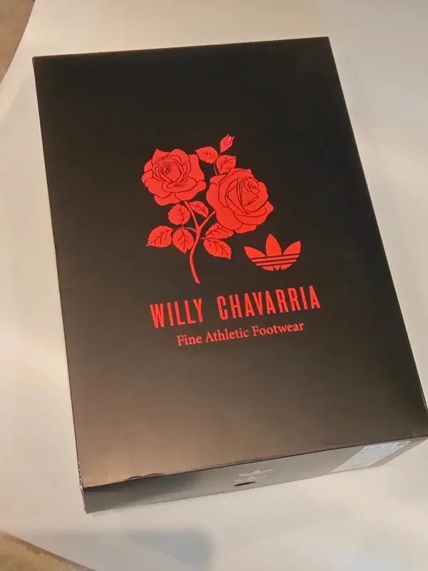 Boîte à chaussures noire de Adidas par Willy Chavarria, avec des roses rouges et le logo trèfle.