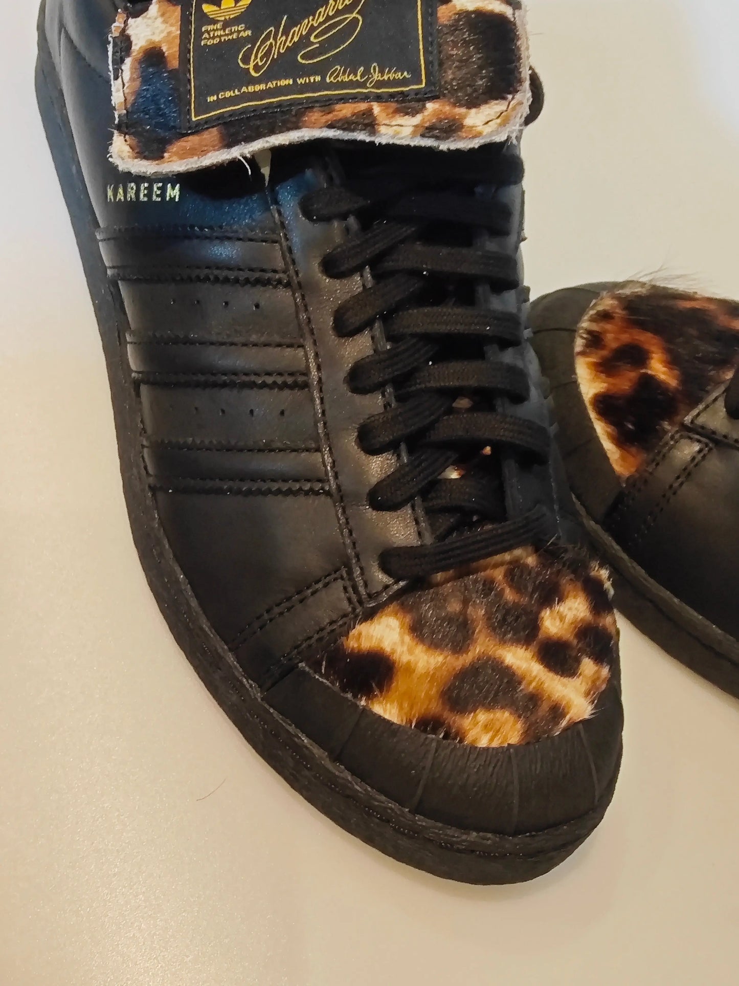 Basket en cuir noir, de Adidas, avec empiècements en motif léopard et inscription « Kareem ».
