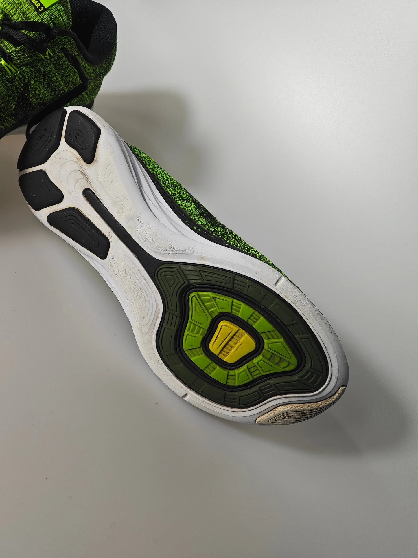 Basket Flyknit vert et noir de Nike, avec semelle intermédiaire blanche et détails texturés.