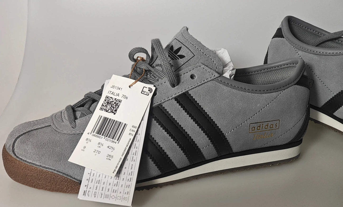 Baskets grises en daim Adidas, avec les trois bandes noires classiques, présentées de profil.