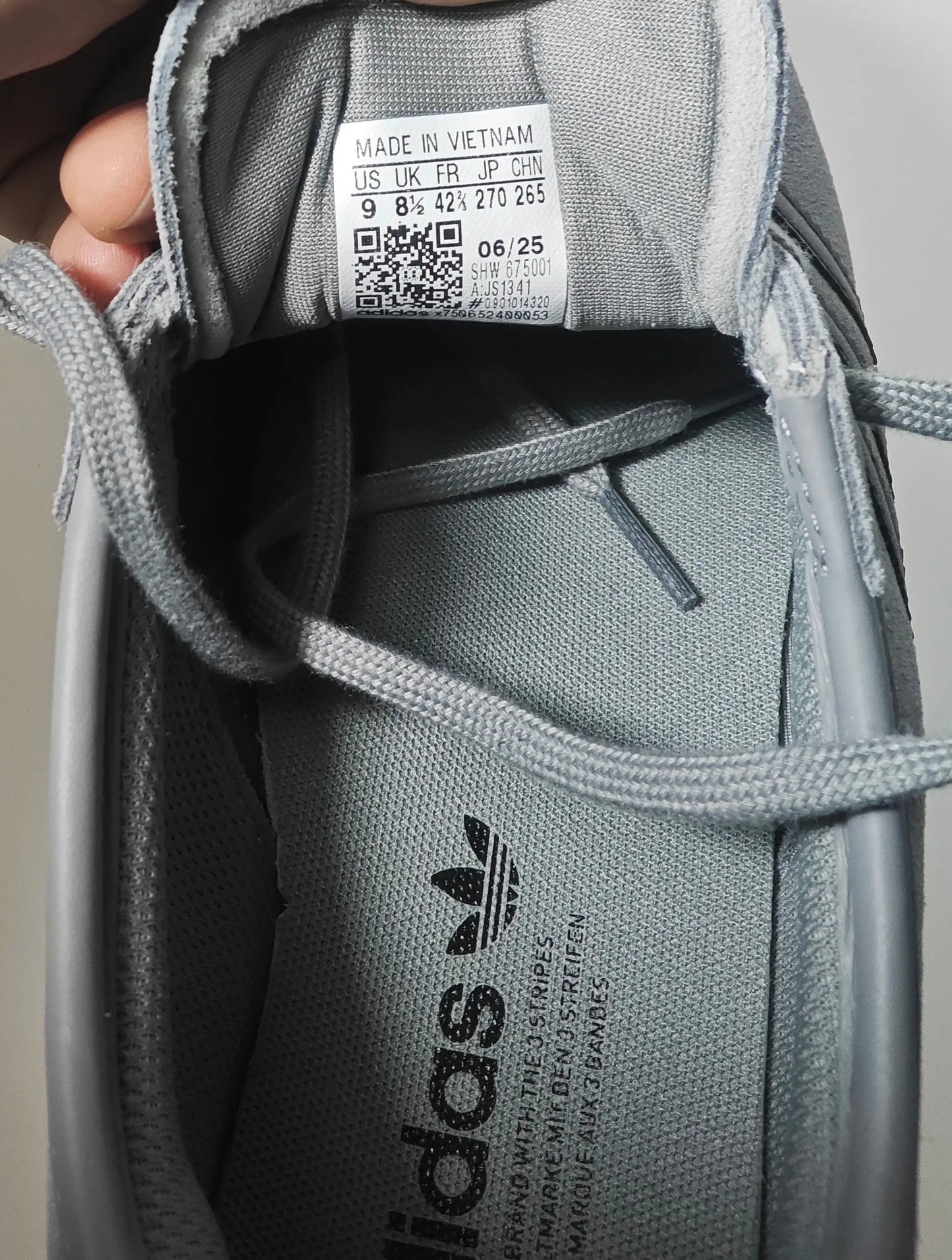 Baskets gris clair Adidas Italia 70s par Adidas, montrant l'intérieur de la chaussure avec logo et étiquette.
