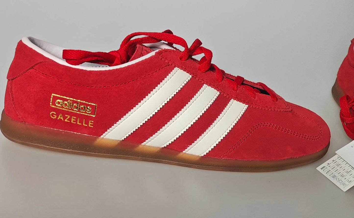 Basket rouge en daim d'Adidas, avec trois bandes blanches et semelle couleur caramel.