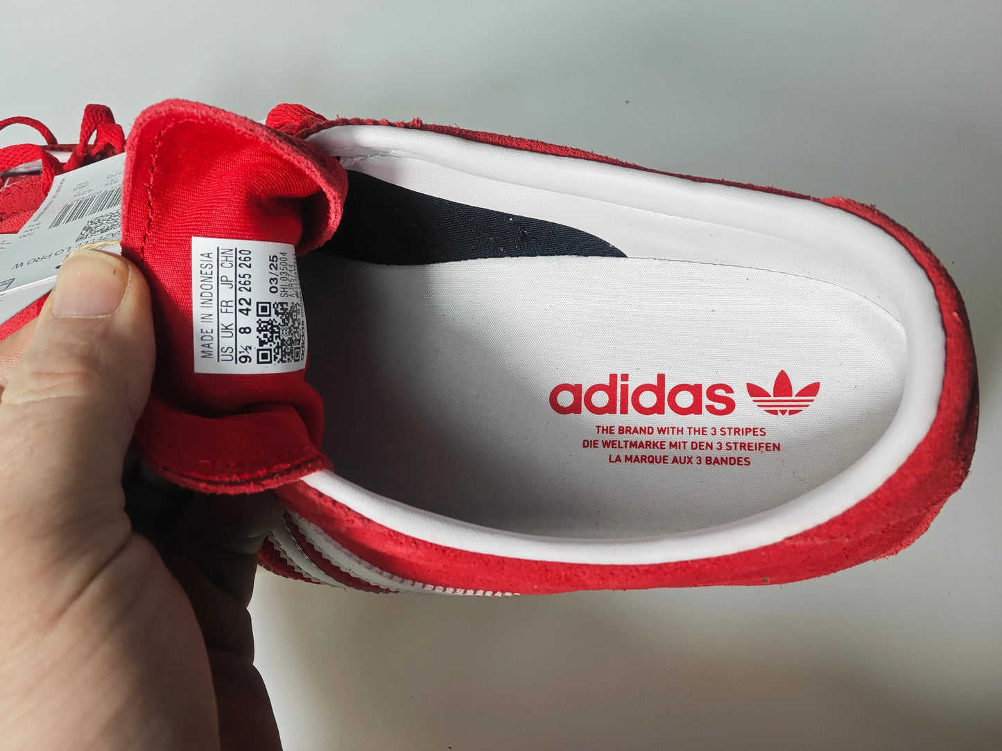 Basket rouge en daim, par Adidas, avec intérieur blanc et logo rouge sur la semelle intérieure.
