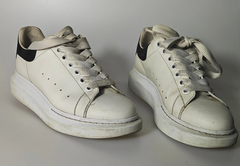 Baskets en cuir blanc à détails noirs par Alexander McQueen, avec des lacets ton sur ton et une semelle épaisse.
