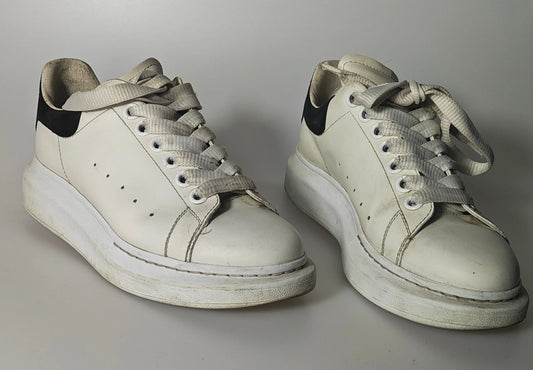 Baskets en cuir blanc à détails noirs par Alexander McQueen, avec des lacets ton sur ton et une semelle épaisse.