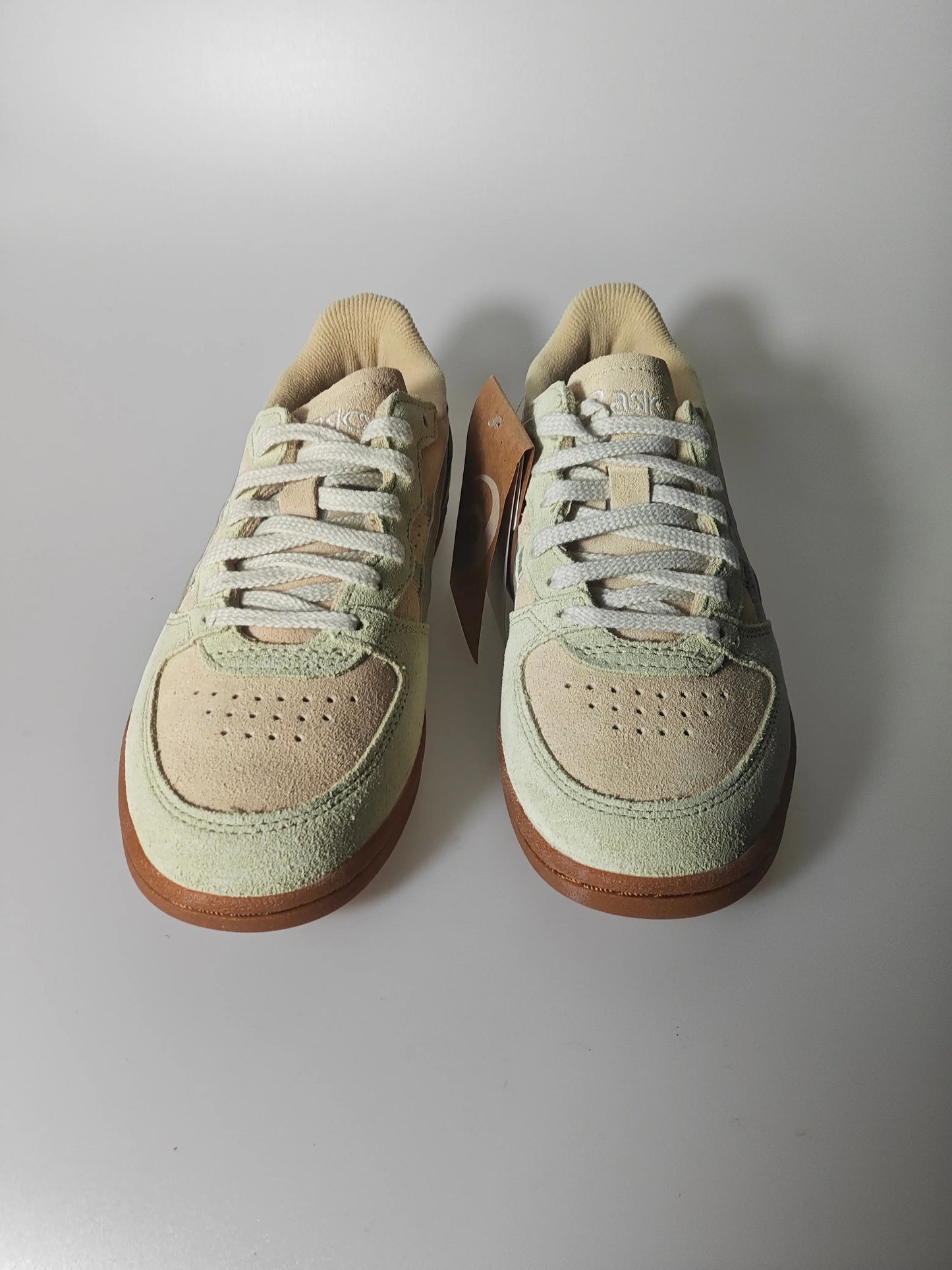 Baskets en daim marron et vert, par ASICS, avec des lacets blancs et semelles en caoutchouc marron.