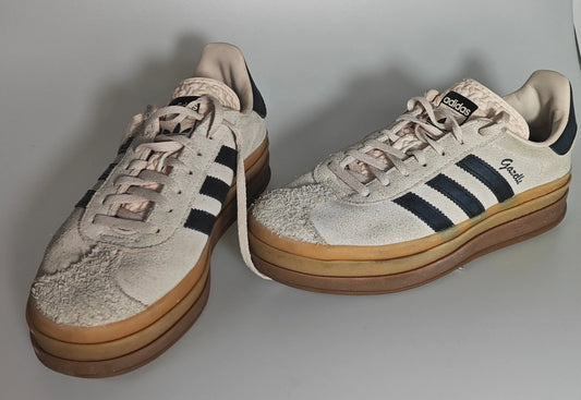 Baskets Gazelle en daim beige, édition spéciale par Adidas, avec semelle plateforme épaisse à rayures et détails noirs.
