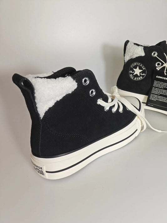 Baskets montantes noires doublées de fourrure par Converse, avec lacets blancs et semelle épaisse.
