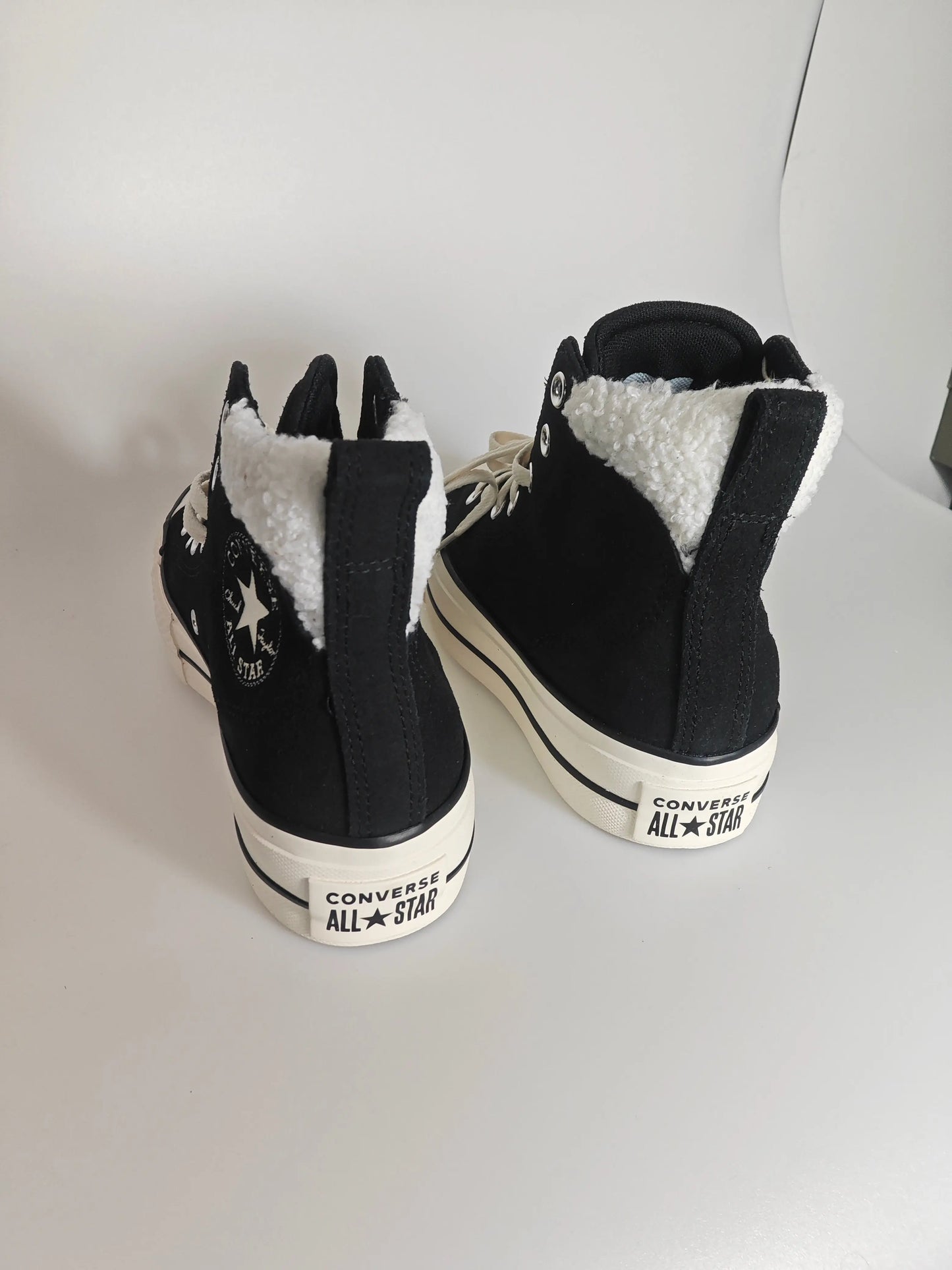 Baskets montantes noires doublées fourrure de Converse, avec logo étoile sur le côté et semelle plateforme.