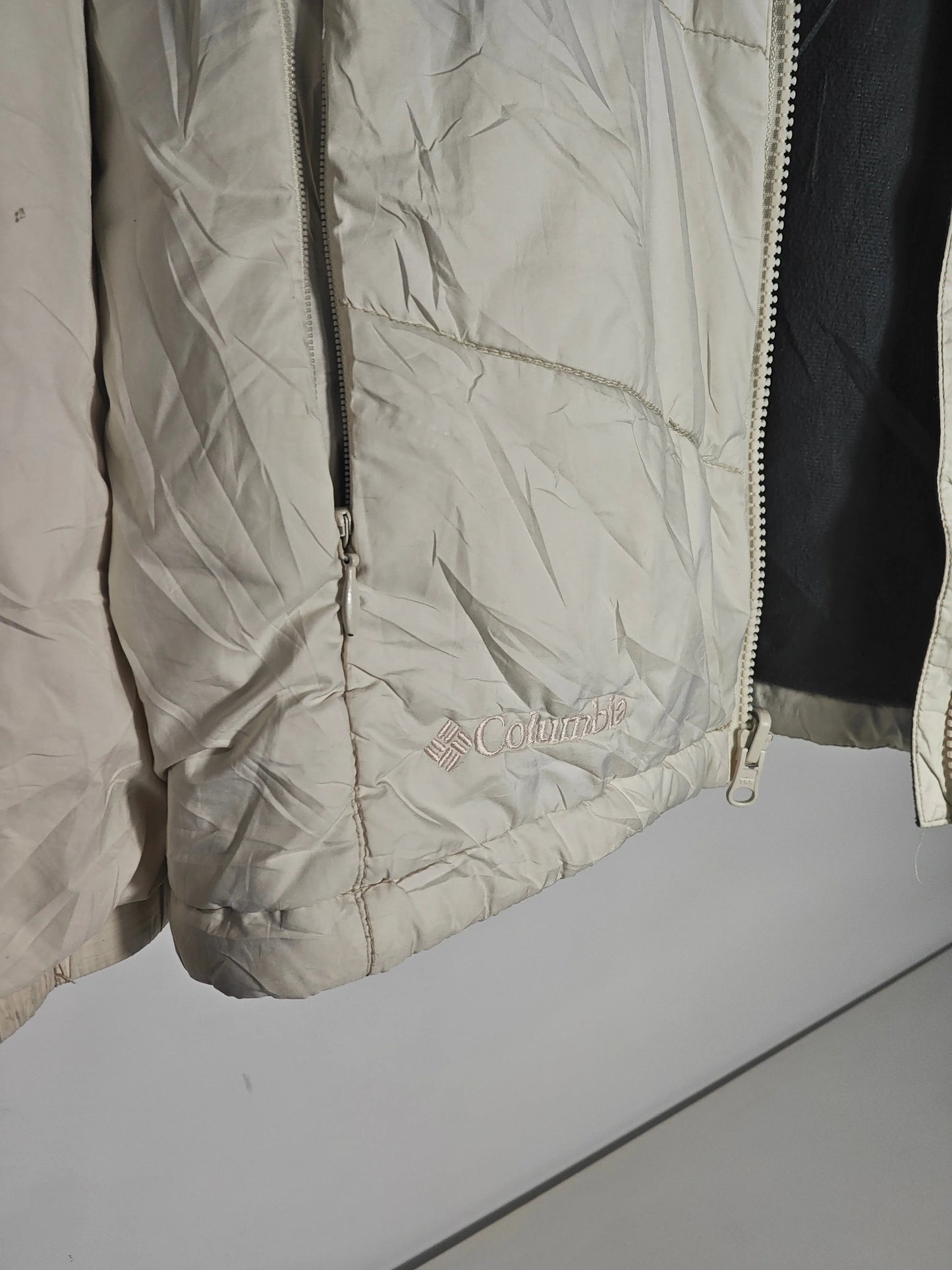 Doudoune beige taille M de Columbia, avec fermeture éclair et logo brodé en bas.