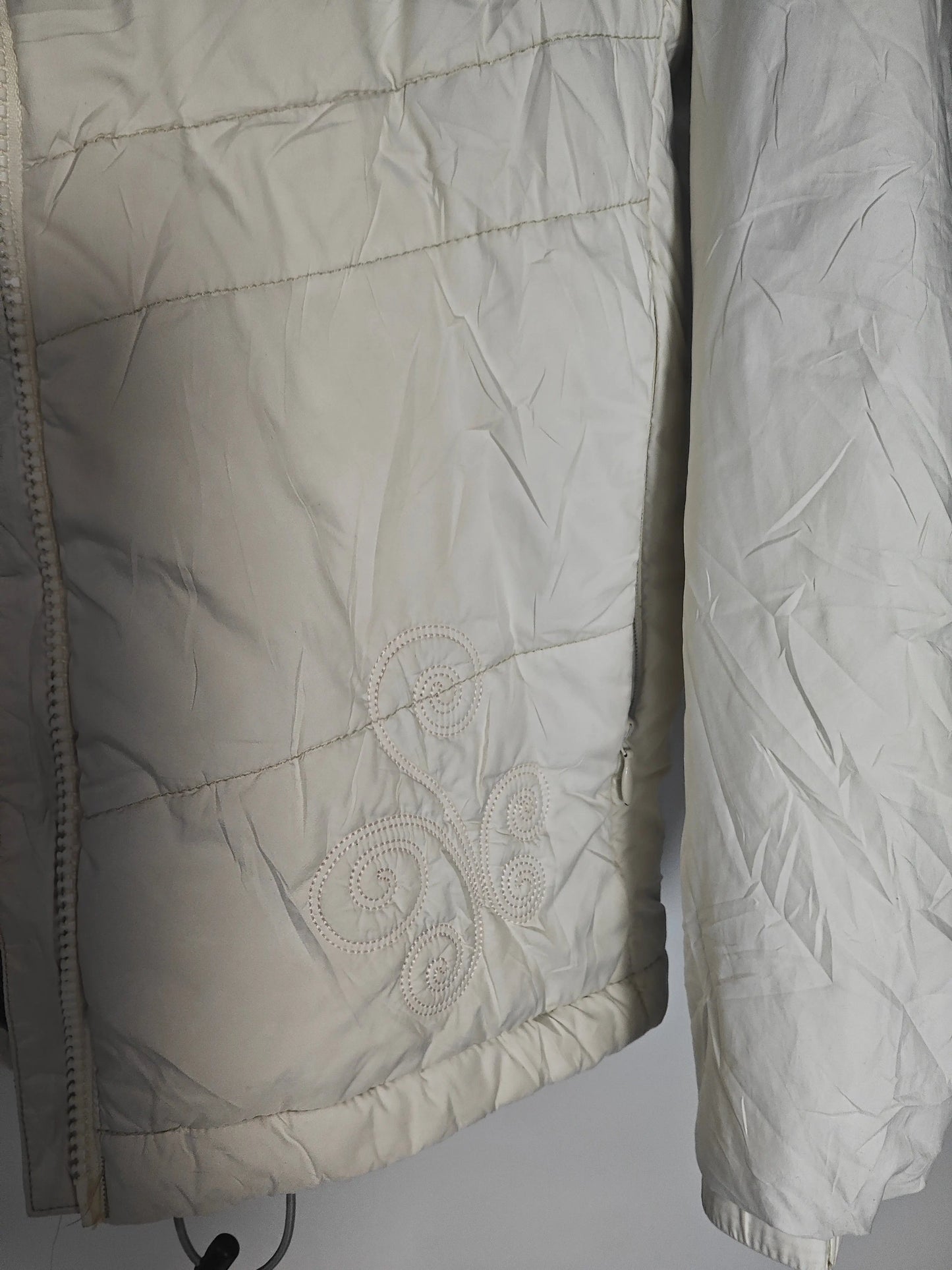 Doudoune blanche Columbia, avec motif floral brodé en spirales ton sur ton, rembourrage matelassé.