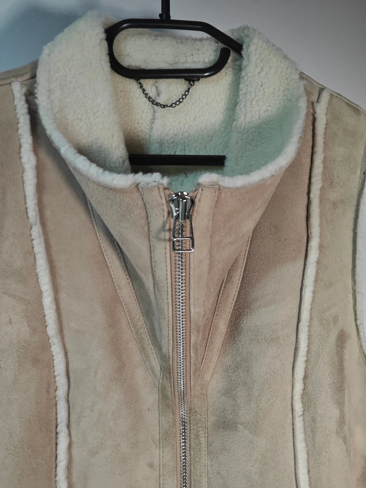 Gilet sans manches en peau lainée beige d'Upstyle Destock, avec fermeture éclair argentée et bordure en fausse fourrure.