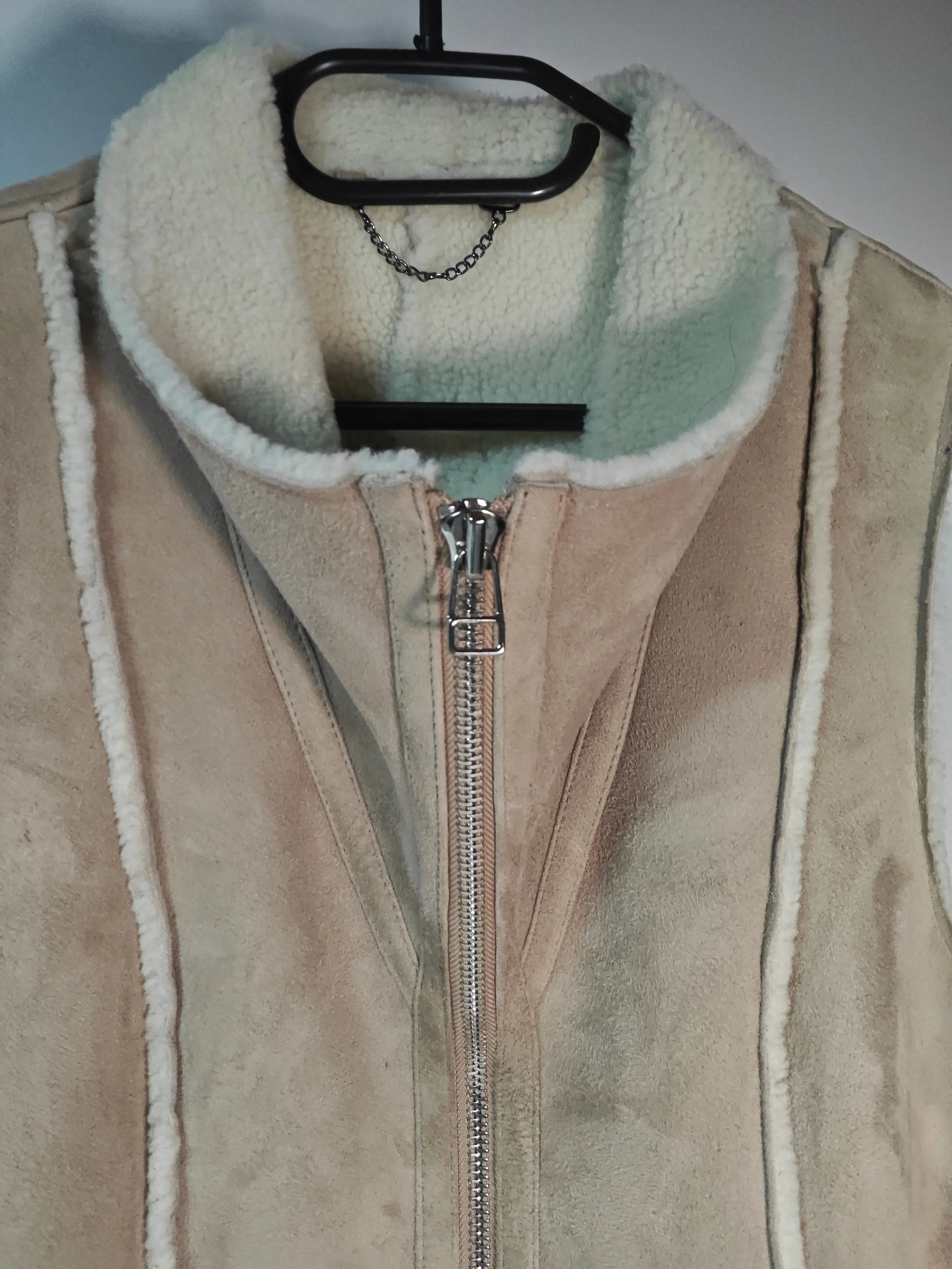Gilet sans manches en peau lainée beige d'Upstyle Destock, avec fermeture éclair argentée et bordure en fausse fourrure.