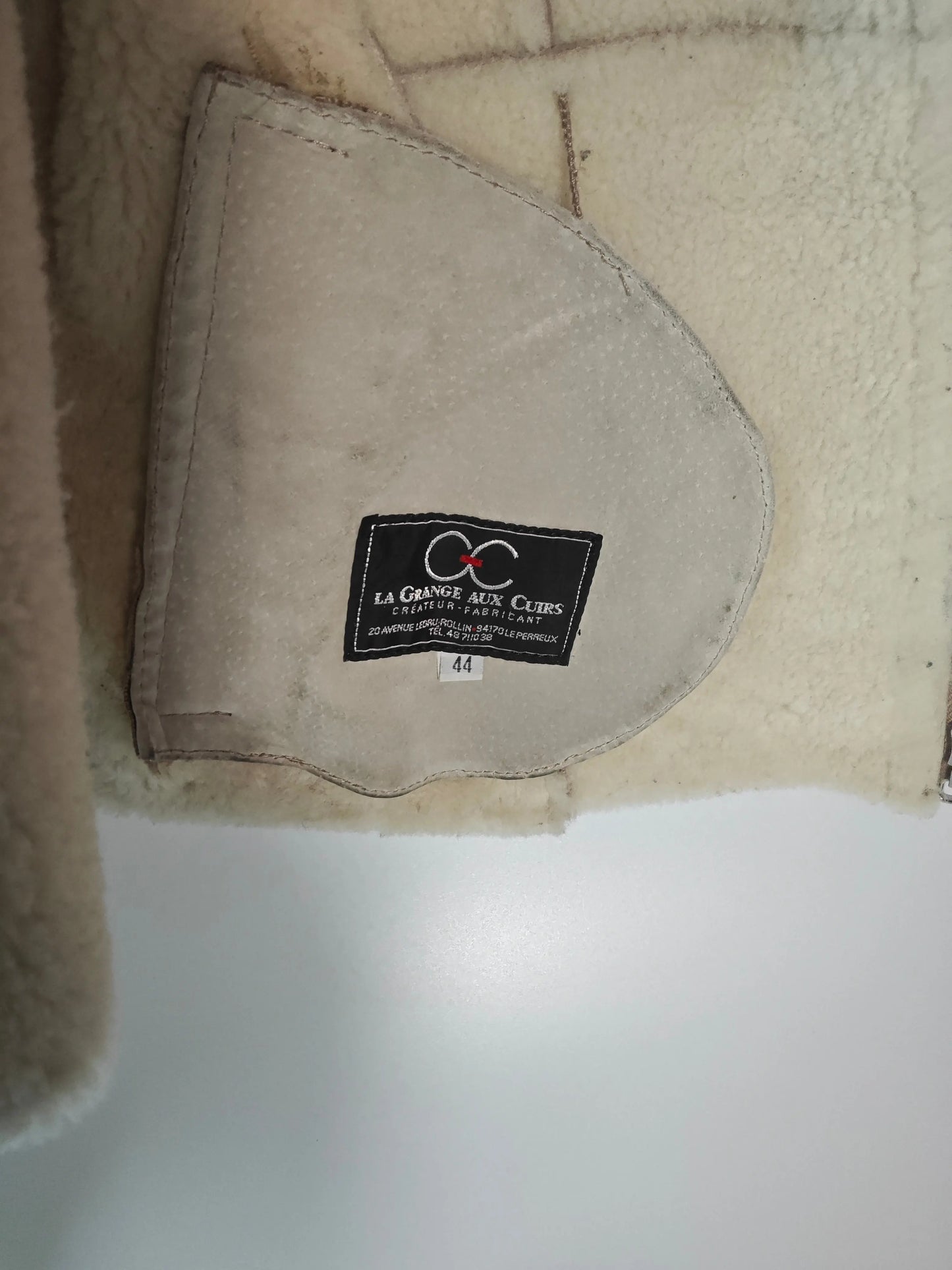 Gilet en peau lainée couleur crème par Upstyle Destock, avec une doublure en peau de mouton texturée et une étiquette noire cousue.
